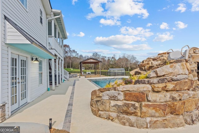 view of swimming pool featuring a gazebo, french doors, and fence