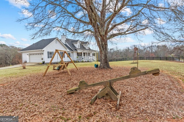 exterior space with a front lawn, a chimney, an attached garage, and fence