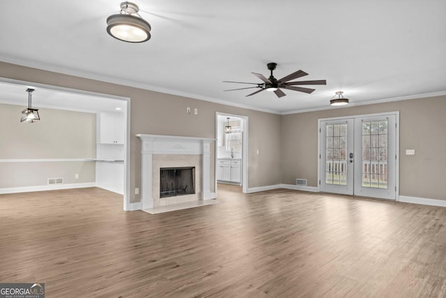 unfurnished living room with french doors, a fireplace, wood finished floors, and visible vents