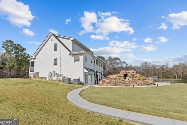 view of home's exterior featuring central AC, a lawn, and fence