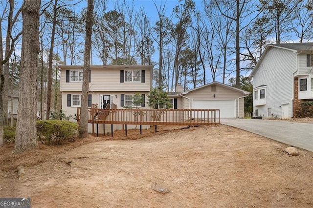 colonial house with a garage, an outdoor structure, driveway, and a wooden deck