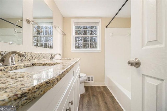 bathroom with toilet, wood finished floors, visible vents, and a healthy amount of sunlight