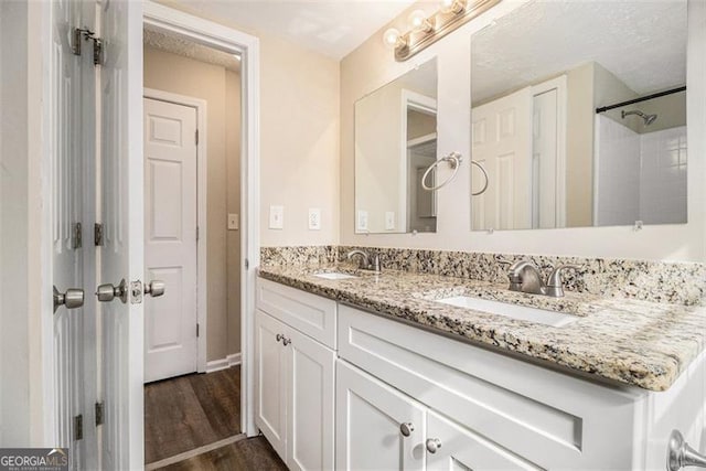 bathroom with double vanity, a sink, and wood finished floors