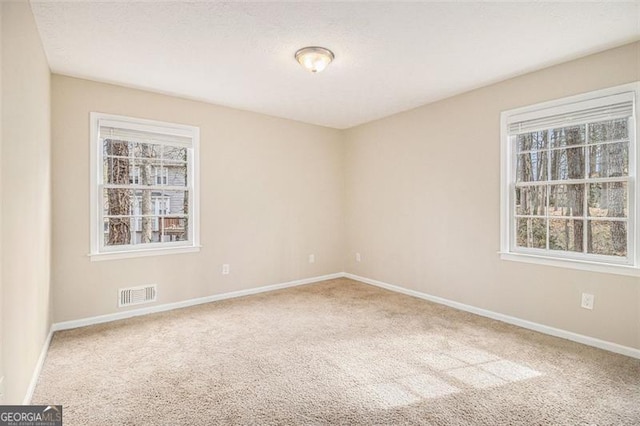 carpeted spare room featuring visible vents, a textured ceiling, and baseboards