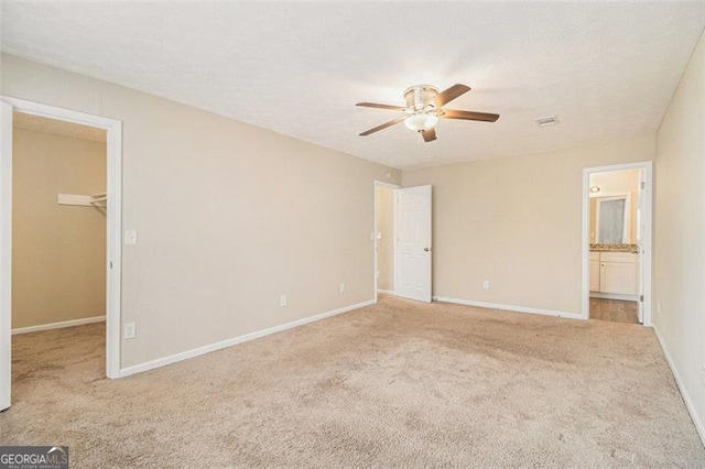 unfurnished bedroom with a walk in closet, baseboards, a textured ceiling, and carpet