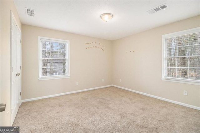 empty room with light colored carpet, a healthy amount of sunlight, and visible vents