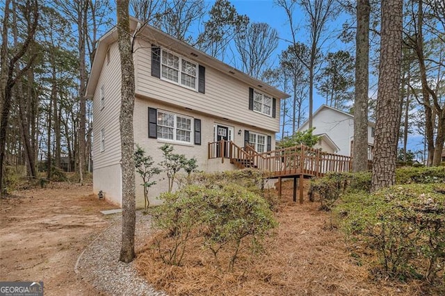 colonial-style house featuring a deck, driveway, brick siding, and an attached garage