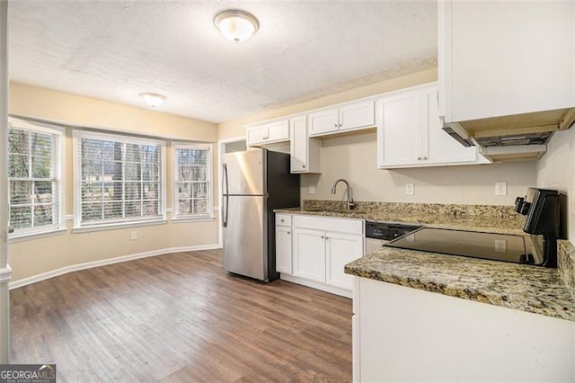 kitchen with white cabinetry, range, a sink, and freestanding refrigerator