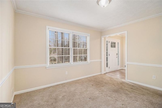 carpeted empty room featuring a textured ceiling, crown molding, and baseboards