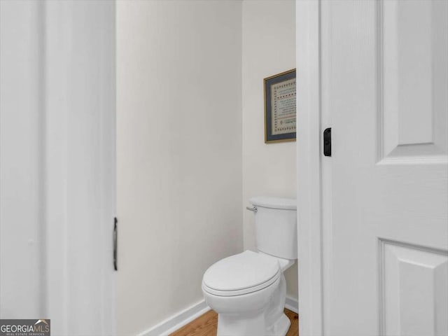 bathroom with baseboards, toilet, and wood finished floors