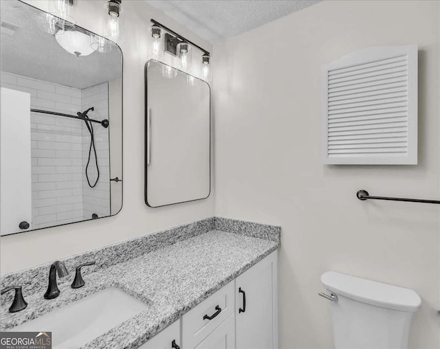 full bath featuring tiled shower, a textured ceiling, toilet, and vanity