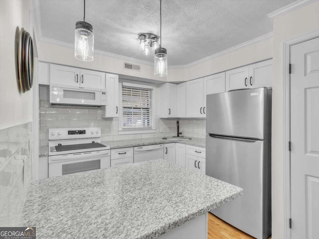 kitchen with white appliances, visible vents, white cabinets, and ornamental molding