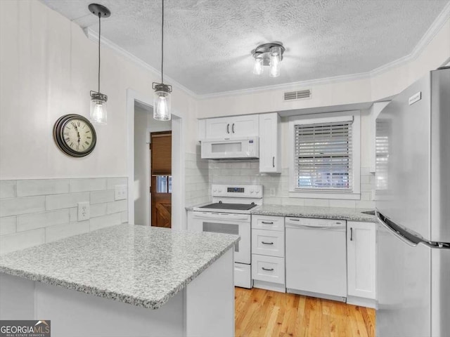 kitchen with white appliances, light wood-style floors, visible vents, and white cabinets