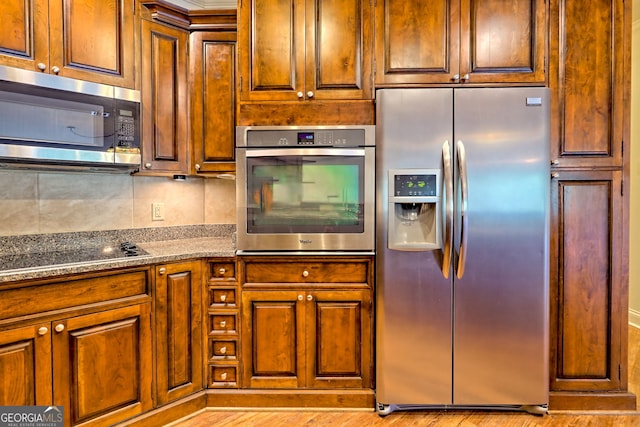 116 Smoky Mountain Ln Unit 103, Clayton, GA 30525 - kitchen featuring appliances with stainless steel finishes, decorative backsplash, brown cabinetry, and stone counters