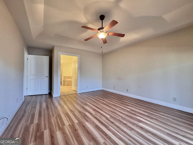 unfurnished bedroom featuring ceiling fan, wood finished floors, connected bathroom, and baseboards