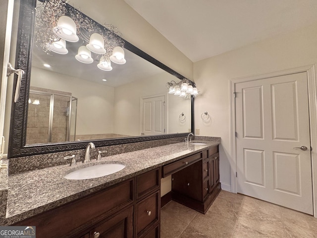 bathroom with double vanity, an inviting chandelier, a shower stall, and a sink