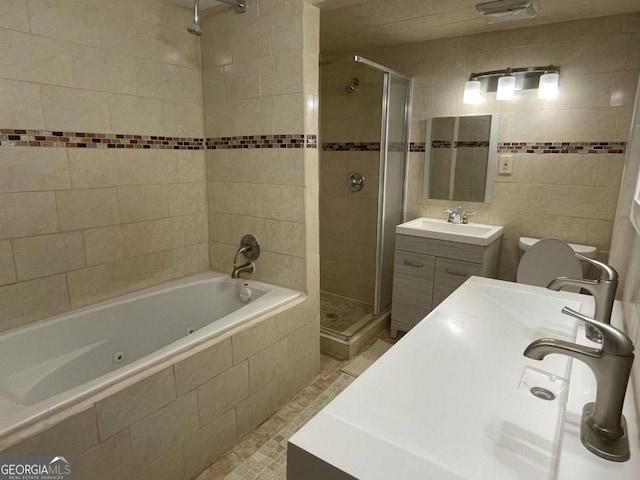 full bath featuring a tub with jets, a stall shower, vanity, and tile walls