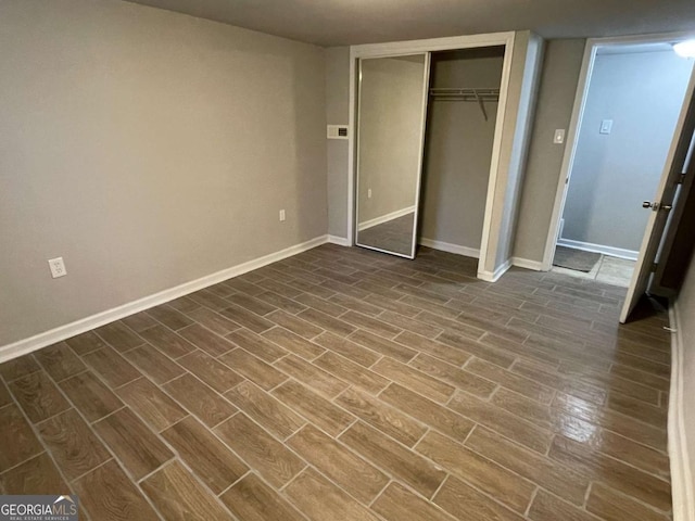 unfurnished bedroom with baseboards, a closet, and wood tiled floor