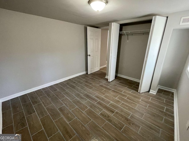 unfurnished bedroom featuring wood tiled floor, a closet, visible vents, and baseboards