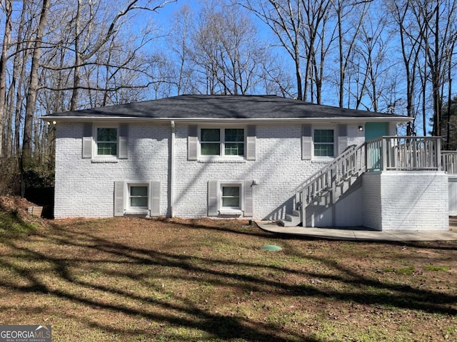 exterior space with brick siding, a yard, and stairs