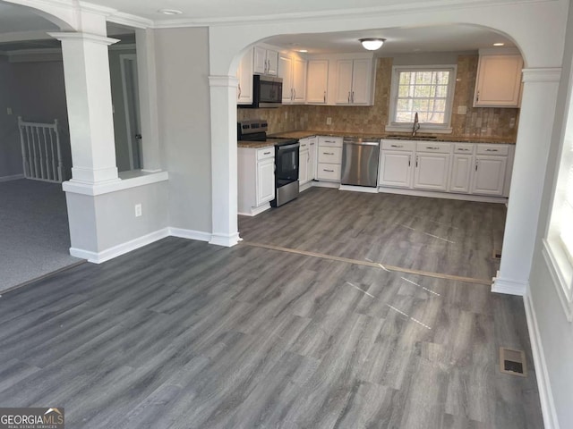 kitchen with dark wood-style flooring, tasteful backsplash, appliances with stainless steel finishes, a sink, and baseboards