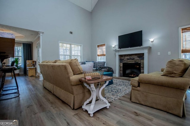 living area featuring high vaulted ceiling, visible vents, a fireplace, and wood finished floors