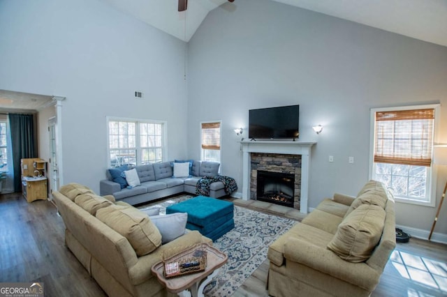 living room featuring a wealth of natural light, a fireplace, baseboards, and wood finished floors