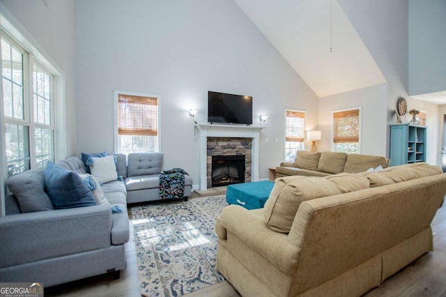 living area with plenty of natural light, a fireplace, high vaulted ceiling, and wood finished floors