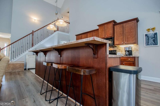 bar featuring high vaulted ceiling, wood finished floors, baseboards, stairs, and backsplash