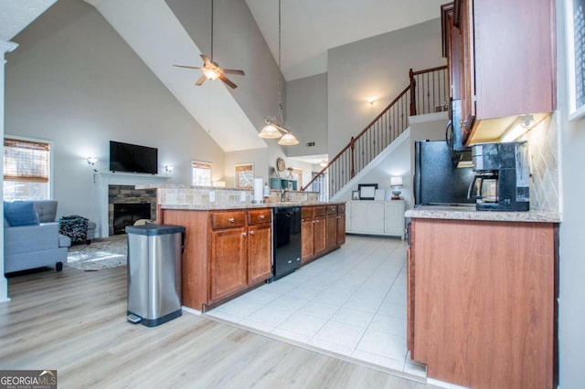 kitchen featuring open floor plan, black appliances, ceiling fan, and a fireplace