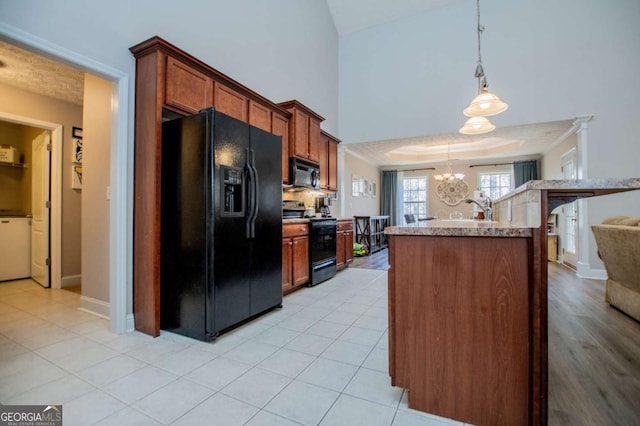 kitchen with brown cabinets, light countertops, hanging light fixtures, a chandelier, and black appliances