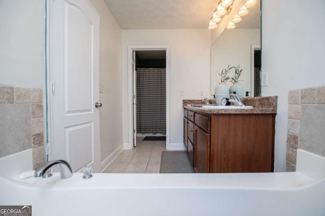 full bath with a textured ceiling, a sink, baseboards, tile patterned floors, and double vanity