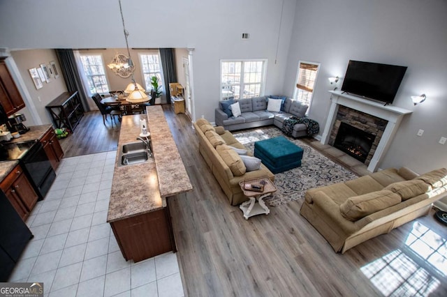 living area with light tile patterned floors, visible vents, a towering ceiling, a fireplace, and a notable chandelier