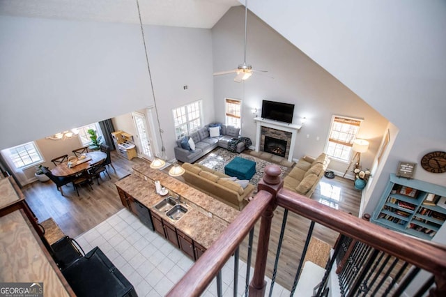 living room with ceiling fan, a fireplace, high vaulted ceiling, and wood finished floors