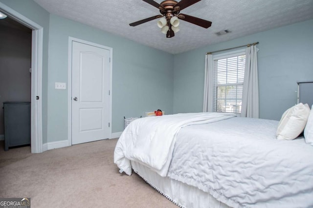 bedroom featuring a textured ceiling, a ceiling fan, visible vents, baseboards, and carpet