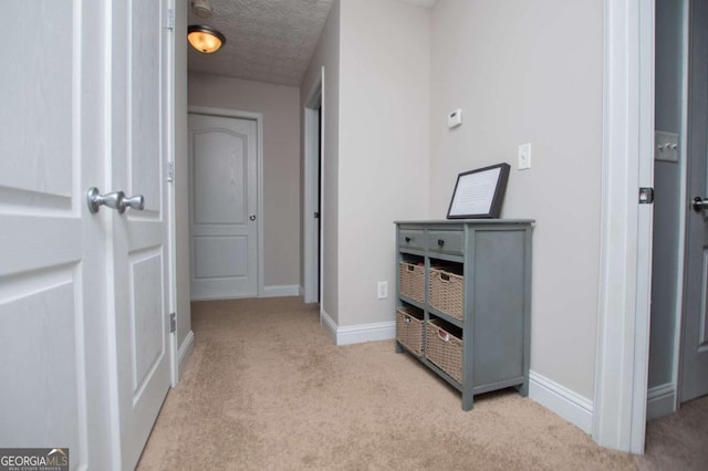 hallway featuring carpet, baseboards, and a textured ceiling