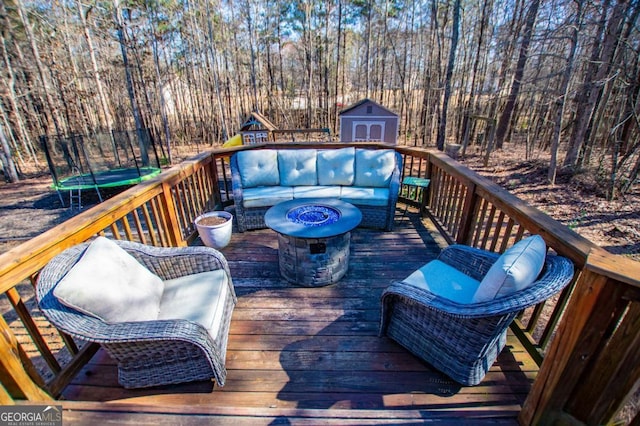 deck with a shed, an outdoor structure, and an outdoor living space with a fire pit