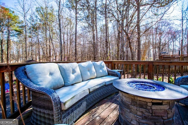 wooden deck featuring an outdoor living space with a fire pit