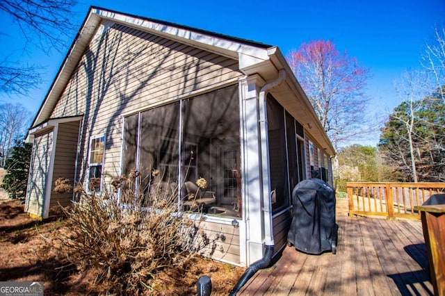 view of property exterior featuring a sunroom and a wooden deck