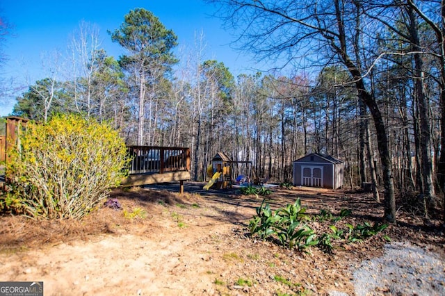 view of yard with a storage shed, an outbuilding, a wooden deck, and a playground