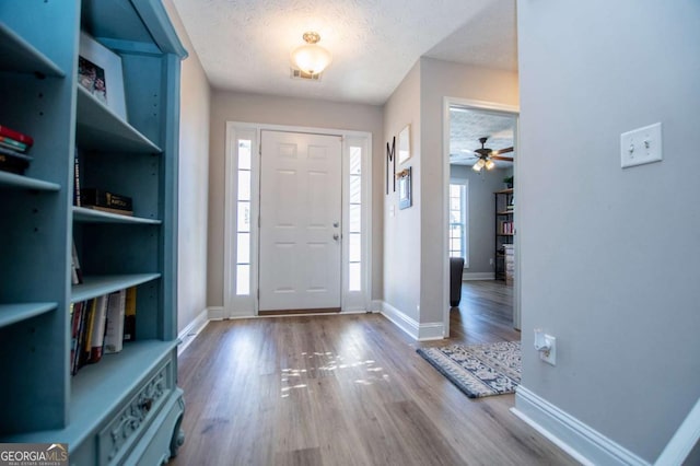 entrance foyer featuring baseboards, a textured ceiling, and wood finished floors