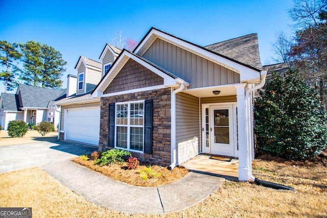 view of front of house with an attached garage, stone siding, driveway, and board and batten siding