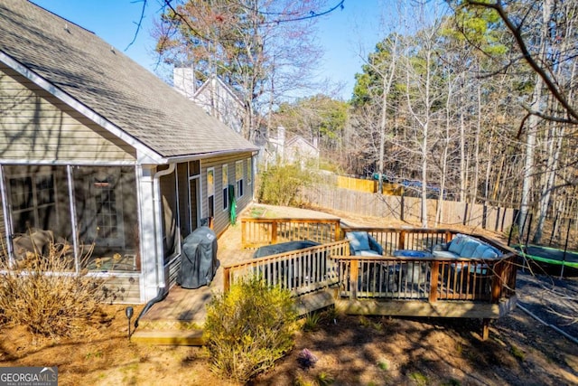 deck featuring a trampoline, area for grilling, and fence