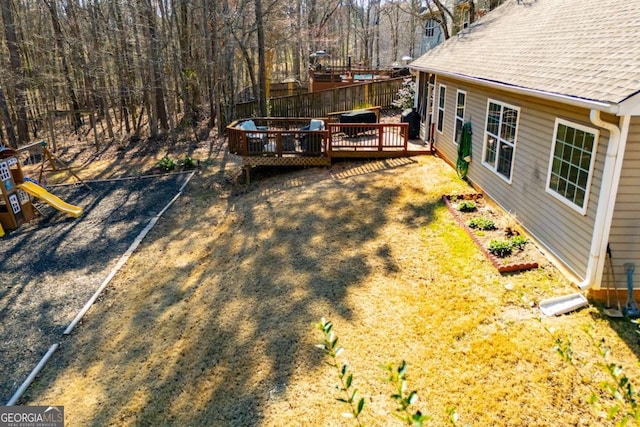 view of yard featuring fence, a deck, and a playground