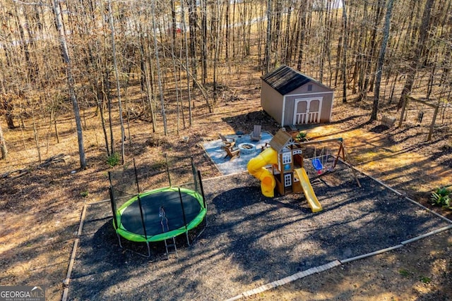 view of jungle gym with a trampoline, a storage unit, and an outdoor structure