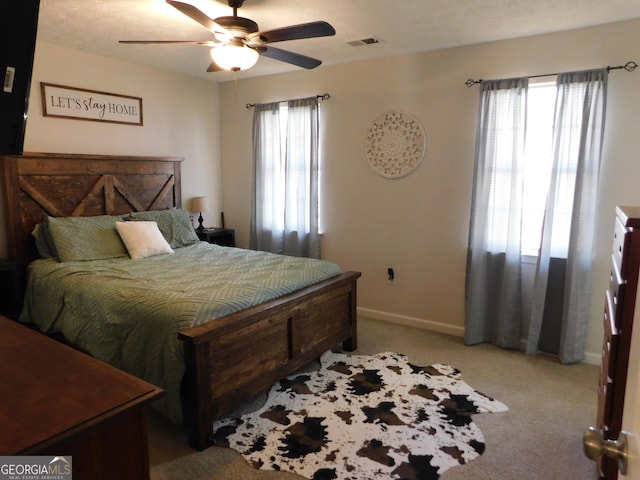 bedroom featuring baseboards, multiple windows, visible vents, and light colored carpet