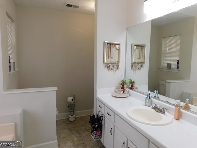 full bath featuring visible vents, vanity, toilet, and baseboards