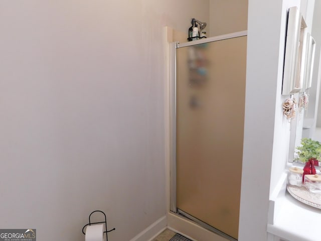 bathroom featuring a shower stall and baseboards