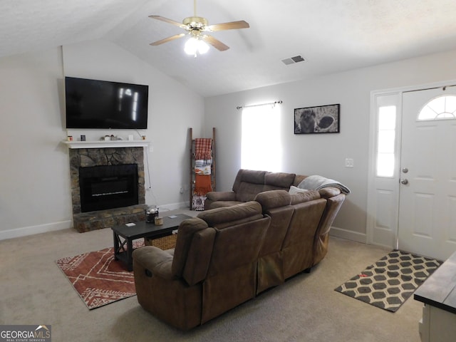 carpeted living room with lofted ceiling, visible vents, a ceiling fan, a stone fireplace, and baseboards