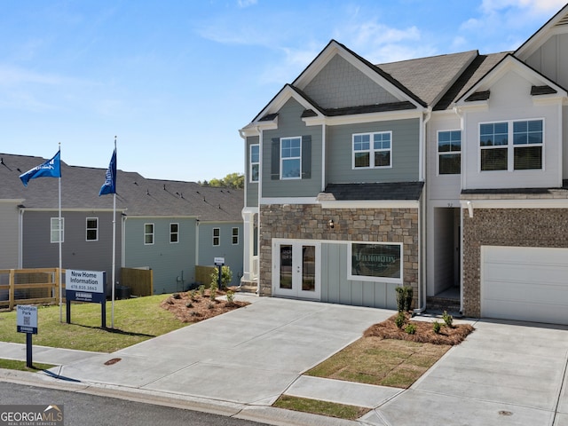 view of front of property featuring stone siding, french doors, driveway, board and batten siding, and a front yard